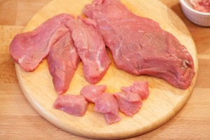 Das Kalbfleisch wird in kleine Stücke geteilt und das Fett abgeschnitten.