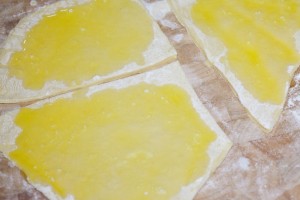 Der ausgerollte Nudelteig wird für die Wickelklöße in vier große Stücke geschnitten, und mit Abstand zum Rand mit Butter bestrichen.