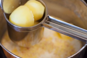 Die Kartoffeln werden mit einer Kartoffelpresse gepresst.