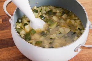 The ready-cooked zucchini soup is pureed with a hand blender.
