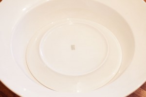 Ein Teller wird mit der Unterseite nach oben in eine große Schüssel gelegt.