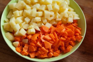 Kartoffeln und Möhren schälen und in kleine Stücke schneiden.