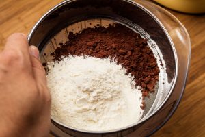 Flour and unsweetened cocoa powder are sifted through.