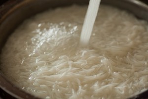 Nach 3 Minuten in kochendem Wasser werden die Reisnudeln abgegossen und mit kaltem Wasser abgespült.