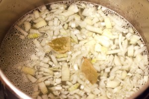 Sobald die Zwiebeln angebraten sind kommen Erbsen, Wasser und Lorbeerblätter in den Kochtopf.