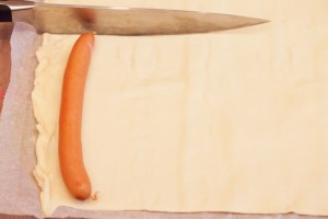 Zugeschnitten wird mit einem scharfen Messer in Länge des einzuwickelnden Würstchens.