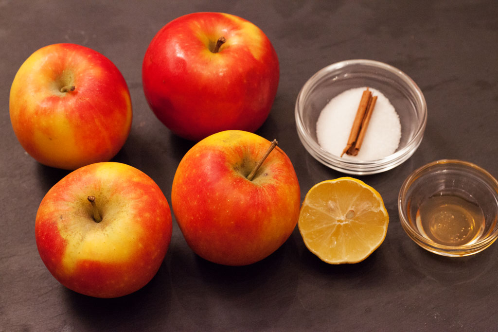 Zutaten für selbstgemachten Apfelmus: Äpfel, Honig, Zucker, Zitronensaft und Zimtstange.