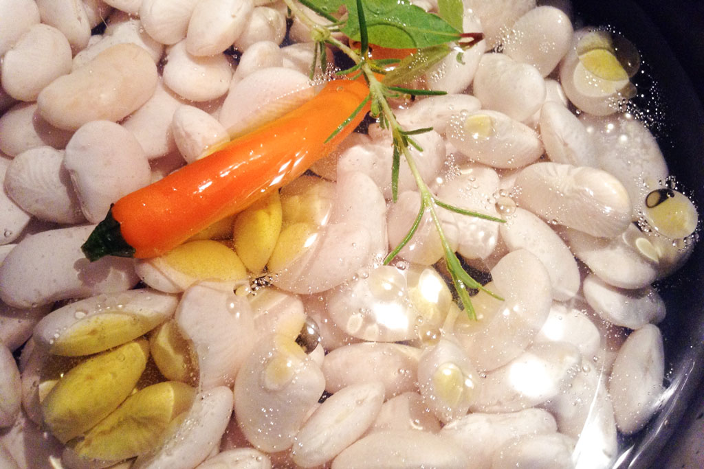 Weiße Bohnen werden mit Rosmarin und Chili aufgekocht.